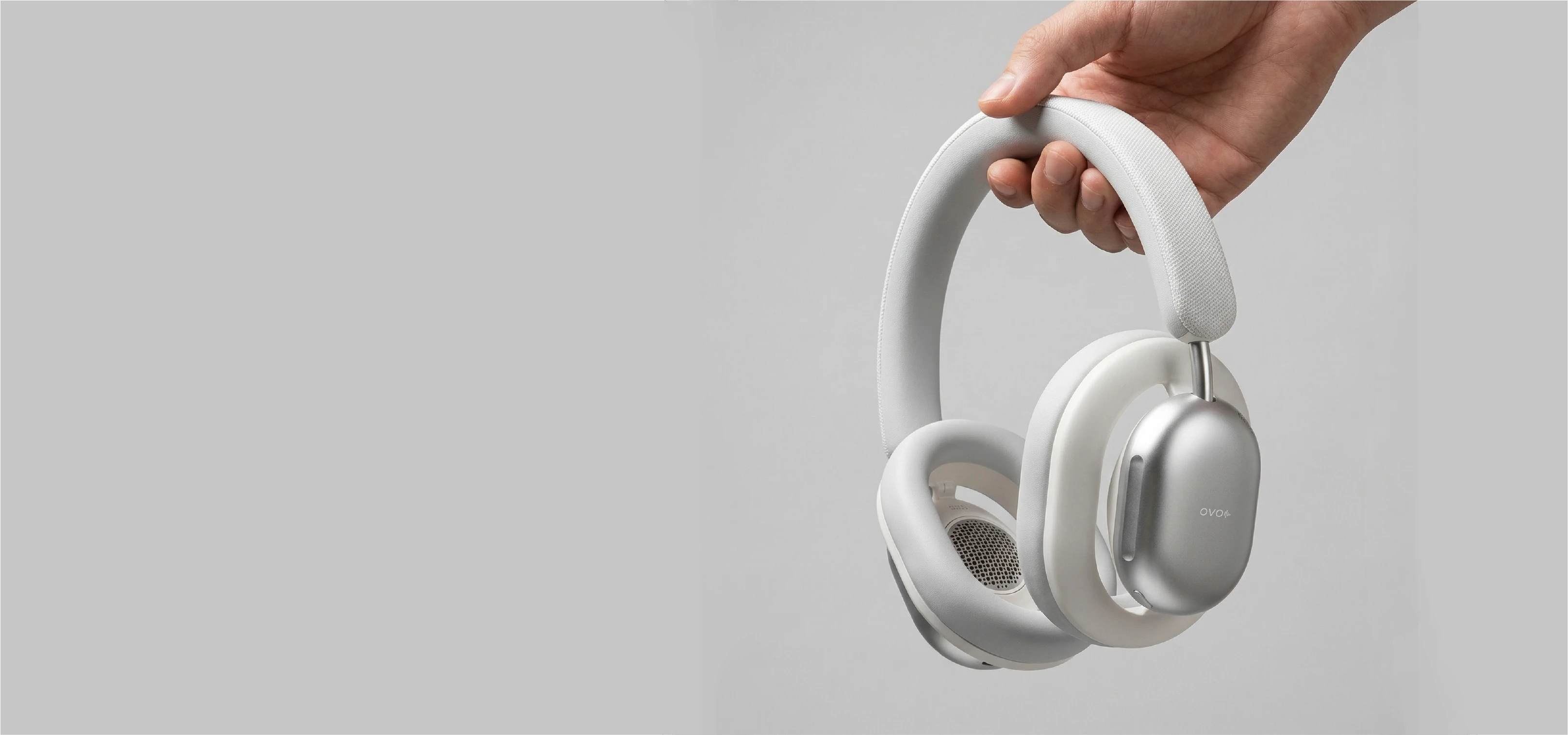 White RELOD OVO Air headphones held by a hand against a gray backgroundslider_item_c9HCXG