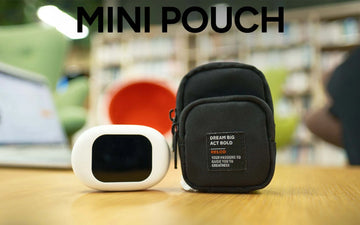 Black mini pouch with motivational quote next to a white device on a wooden surface.